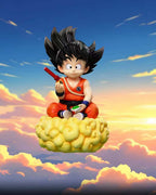 A collectible figurine of Son Goku from Dragon Ball sitting on his yellow cloud mount, set against a dramatic sunset sky with clouds. The image features promotional text and branding for C-PR.