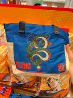 A blue Dragon Ball tote bag with an embroidered green and white dragon design, red 'GABENRON' text, and a red character emblem, held by a hand in a retail store setting.