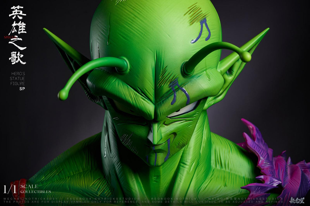 A close-up collectible figure of the Dragon Ball Z character Piccolo, shown from the chest up against a dark studio background. The figure has a bright green skin tone, pointed ears, and a small purple flower detail on the right side of the frame.